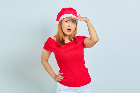 Photo of beautiful Asian girl in christmas hat with surprise fasial expression and open mouth on white background