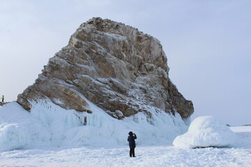 Baikal lake in winter. Woman taking photos of ice formations