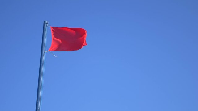 Red waving flag with blue sky background. Slow Motion HD