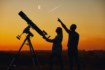 Couple stargazing together with a astronomical telescope, looking at planets, stars, lunar eclipse...