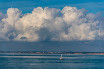 Obraz premium Cloud scape, with sailing boat in the sea