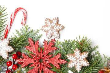 Christmas decoration. Christmas tree branches, red berries and snow flake shaped cookies on white background.