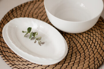 various white plates and a branch of eucalyptus on a jute napkin