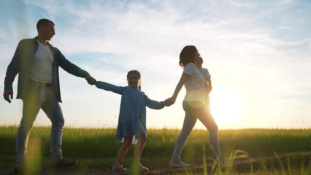 Happy family is walking on green grass.Family walk along rural road. Children with parents outdoors in park. Group of people are walking on grass in field. Happy family concept in park