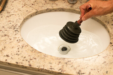 Man Using a Plunger to unstop his bathroom sink 