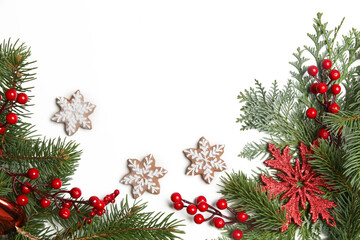 Christmas decoration. Christmas tree branches, red berries and snow flake shaped cookies on white background.