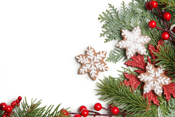 Christmas decoration. Christmas tree branches, red berries and snow flake shaped cookies on white background.
