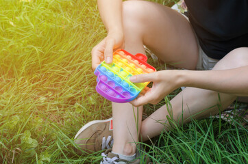 Unrecognizable woman playing with a pop it toy in nature