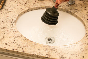 Man Using a Plunger to unstop his bathroom sink 
