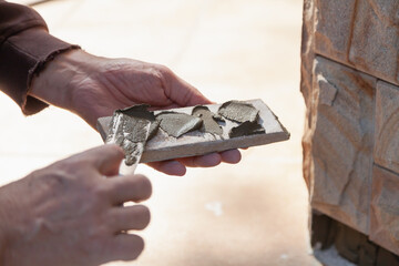 Hand applies mortar to stone tiles close-up..