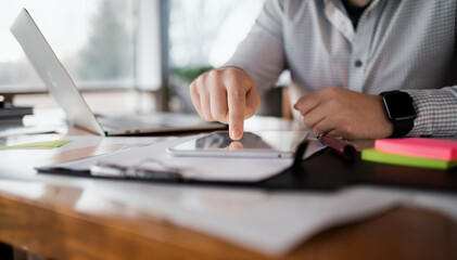 A man makes a financial report in the company. Surf the Internet on a laptop. The economist considers the costs of a startup. Manager workplace in a bright office.