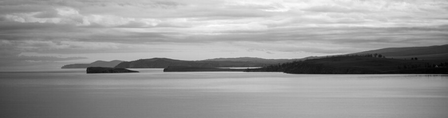 Great view on the lake with islands in cloudy day. Panorama landscape in sunny evening.