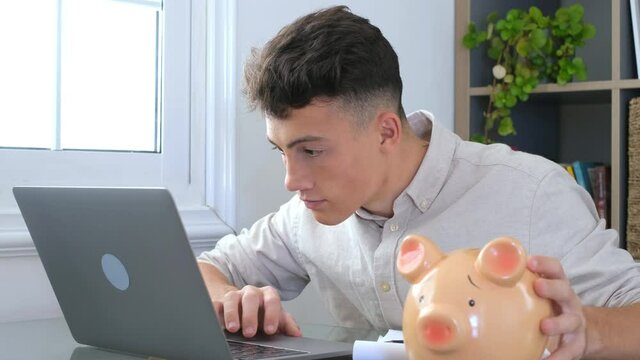 Man sit at desk manage expenses, calculate expenditures, pay bills online use laptop, makes household finances analysis, close up focus on pink piggy bank. Save money for future, be provident concept
