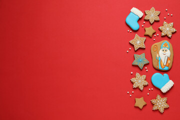Fototapeta na wymiar Tasty gingerbread cookies on red background, flat lay with space for text. St. Nicholas Day celebration