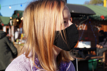 portrait of a teenage girl in a black medical mask on the street
