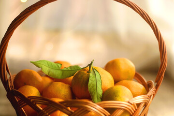 Vintage basket filled with fresh tangerines. Bokeh lights in the background. Selective focus.