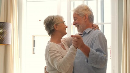 Happy and funny couple of old and mature people having fun and enjoying at home doing a party together singing and dancing playing the guitar indoor. Holiday or event celebrating concept.
 - Powered by Adobe