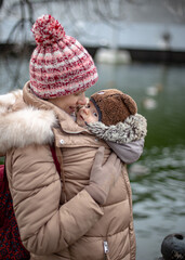 Mom with a small child is walking in the park. The child sits under the jacket of the mother in a...
