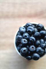 Cup of fresh blueberries on wooden table. Flat lay.