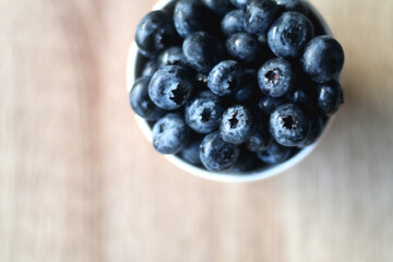 Cup of fresh blueberries on wooden table. Flat lay.