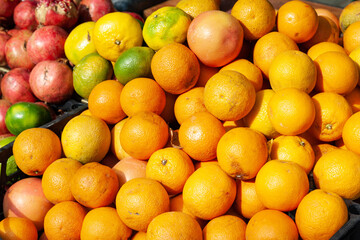 Heap of oranges. Oranges and pomegranates are stacked in a box. Street trade. Healthy food.