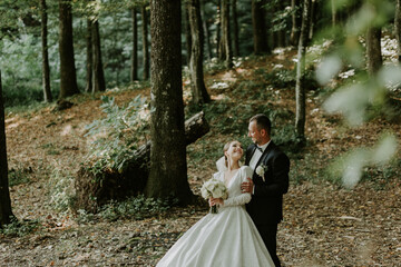 The groom tenderly hugs his bride behind her. The bride looks at her husband and smiles