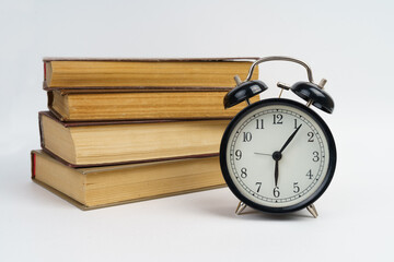Books and an alarm clock lie on a white background.