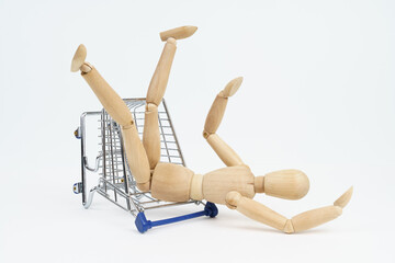 The wooden man fell to the floor from the shopping trolley. Isolated on white background.