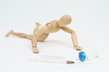 The wooden man crawls towards the syringe and injection. Isolated on white background.