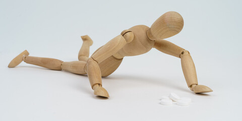 The wooden man crawls for pills. Isolated on white background.