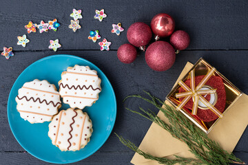 Gingerbread cookies on a plate, on a wooden background, top view, new year holidays, christmas, candle and christmas balls, gifts