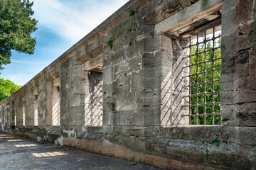 A row of antique barred windows. Ancient wall of gray stone.  Historical sights and tourist locations.