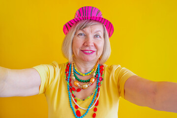 Happy crazy senior woman blogger taking selfie having fun while wearing stylish clothes. Grandmother portrait. Concepts about new adults