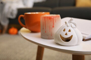 Halloween decor and cup of delicious drink on white table in room