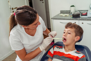 Attractive dentist performs a simple eye examination of the young patient's mouth. Concept dental care, health care.