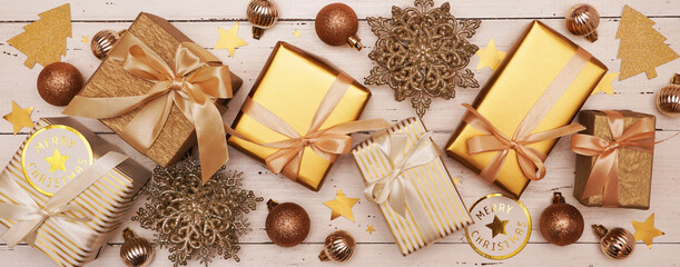  Christmas or New Year Decoration, background. Ornament with gold gift boxes, Christmas baubles, snowflakes and stars on an old white wooden table. Banner.