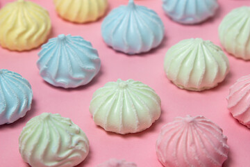 Multicolored meringues on a pink background. Meringue of different colors folded in several rows by color