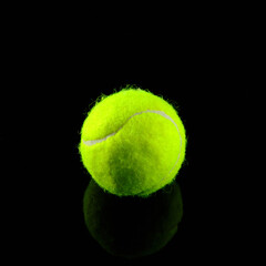 Tennis ball at black glossy surface and black background