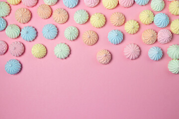 Multicolored meringues on a pink background. Dessert on a bright background, there is a place for copy space