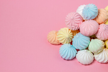 Multicolored meringues on a pink background. A pile of meringues on a bright background, there is a place for copy space
