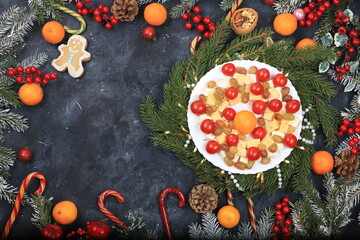 Christmas new year dishes, traditional holiday salad of cheese, tangerines, grapes and honey, for vegan food, fir branches and cones and decorations, food design idea, place for recipe, flat lay,