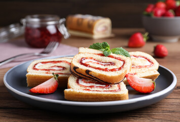 Tasty cake roll with strawberry jam and cream on wooden table, closeup