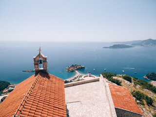 Fototapeta na wymiar The bride and groom are sitting embracing on the observation deck overlooking the island of Sveti Stefan near the ancient monastery