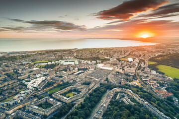 Sunrise over the city lights of Edinburgh. Aerial view of Edinburgh as the sun rises over the city. Early morning mist creeps along the shoreline of the North Sea like steam from a brewed coffee