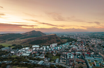 Aerial sunrise view of Calton Hill in Edinburgh, Scotland surrounded by old buildings. Locals use the hill to observe the vastness of the city, enjoy festivals, or attend to spiritual activities