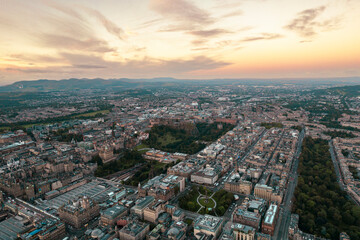 Fototapeta na wymiar Aerial view of Edinburgh cityscape as sun rises over the city. Old city wakes up with the sunrise. Early morning haze lifts as the first rays of sunlight hit the city of Edinburgh, Scotland