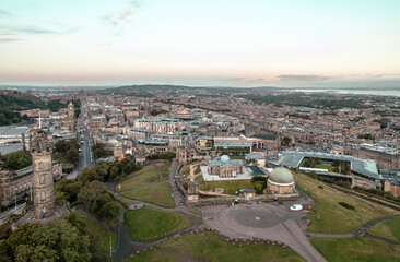 Fototapeta na wymiar Aerial sunrise view of Calton Hill in Edinburgh, Scotland surrounded by old buildings. Locals use the hill to observe the vastness of the city, enjoy festivals, or attend to spiritual activities