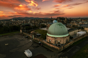 Obraz premium Aerial sunrise view of Calton Hill in Edinburgh, Scotland surrounded by old buildings. Locals use the hill to observe the vastness of the city, enjoy festivals, or attend to spiritual activities