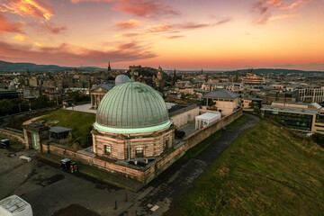 Obraz premium Aerial sunrise view of Calton Hill in Edinburgh, Scotland surrounded by old buildings. Locals use the hill to observe the vastness of the city, enjoy festivals, or attend to spiritual activities