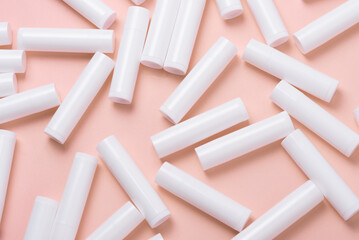 Lot of white plastic lip gloss tubes on pink background - obrazy, fototapety, plakaty